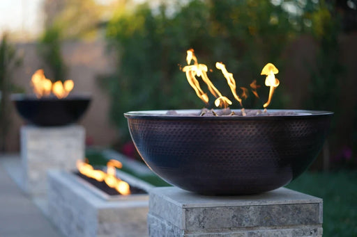 the outdoor plus sedona 27 inch copper fire and water bowl exterior view

the outdoor plus sedona hammered copper fire water bowl lit on patio night

the outdoor plus sedona fire water bowl poolside setup with flame and water spillway

the outdoor plus sedona copper fire bowl stainless steel burner close-up
